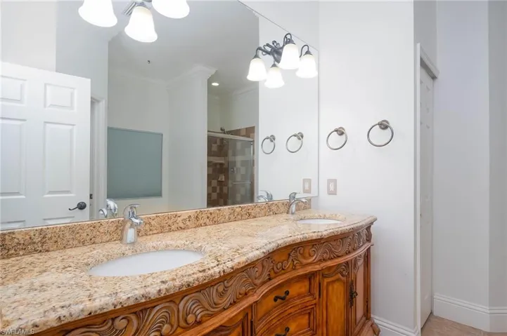 Bathroom featuring tile patterned flooring, vanity, an enclosed shower, and crown molding