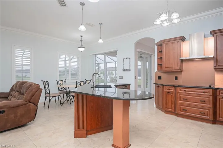 Kitchen featuring wall chimney exhaust hood, sink, pendant lighting, and ornamental molding