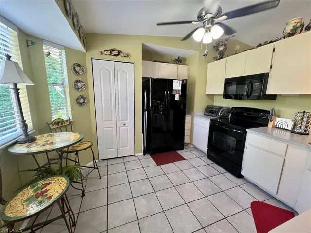 Tiled eat in kitchen featuring ceiling fan and lofted ceiling