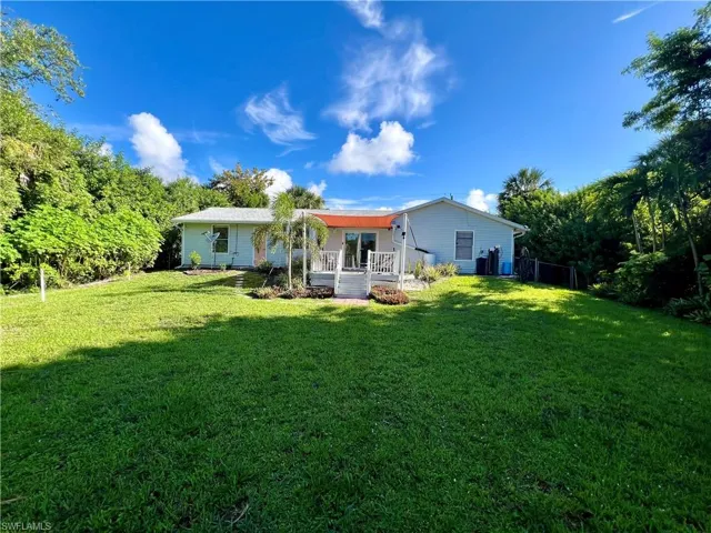 Rear view of property with a porch and a lawn