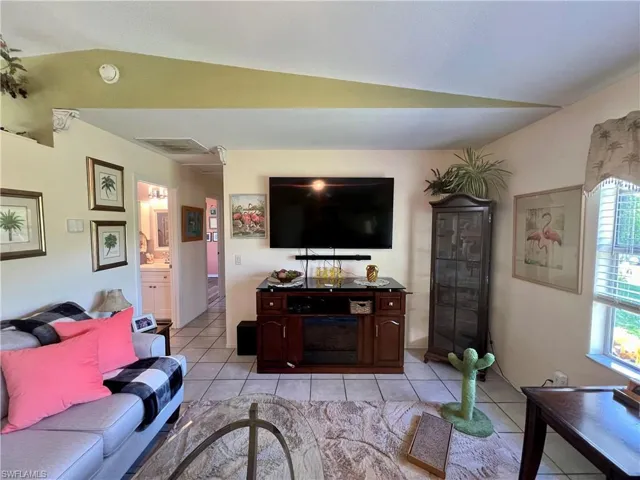 Living room with tile flooring, ceiling fan, and lofted ceiling
