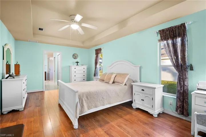 Bedroom featuring a tray ceiling, hardwood / wood-style floors, and ceiling fan