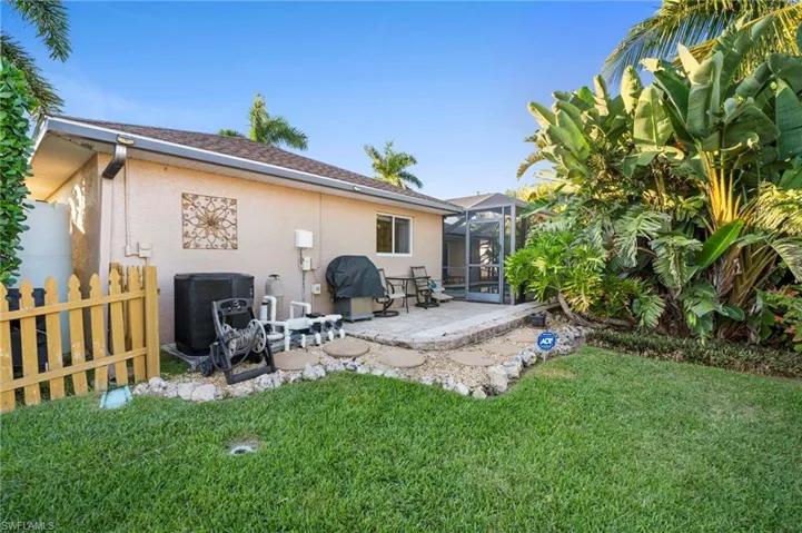 Back of property with a patio, glass enclosure, a lawn, stucco siding, and a shingled roof