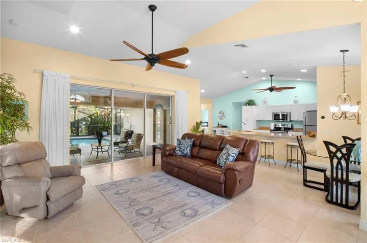 Living room featuring vaulted ceiling, light tile patterned floors, a chandelier, a ceiling fan, and recessed lighting