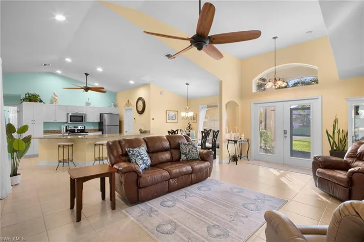 Living area with a ceiling fan, high vaulted ceiling, a chandelier, light tile patterned floors, and plenty of natural light