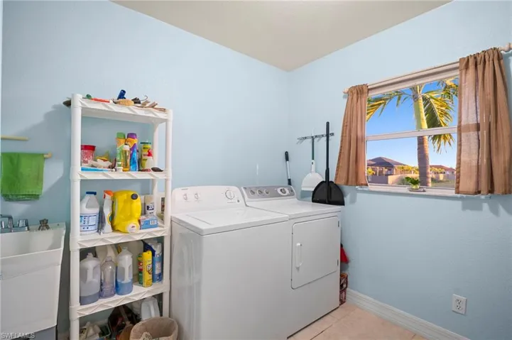 Laundry area featuring light tile patterned flooring and independent washer and dryer