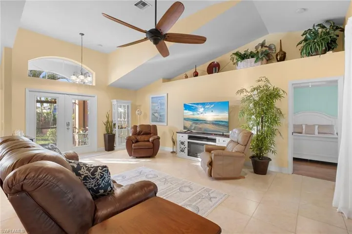 Living area featuring a ceiling fan, a chandelier, french doors, high vaulted ceiling, and light tile patterned floors