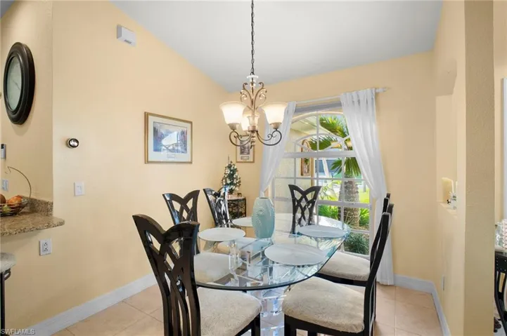 Dining area with light tile patterned flooring, lofted ceiling, and a chandelier