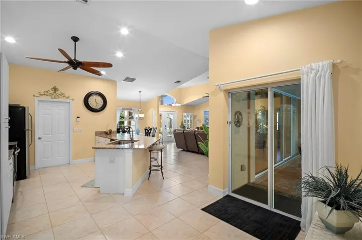 Kitchen featuring a breakfast bar area, dark stone countertops, lofted ceiling, recessed lighting, and a center island with sink