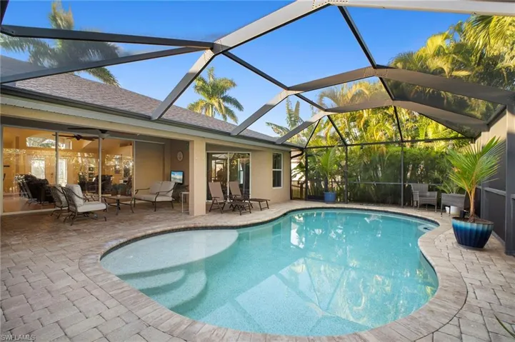 Outdoor pool featuring a sunroom, glass enclosure, and a patio