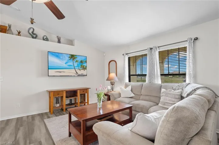 Living room featuring ceiling fan, light hardwood / wood-style floors, and vaulted ceiling