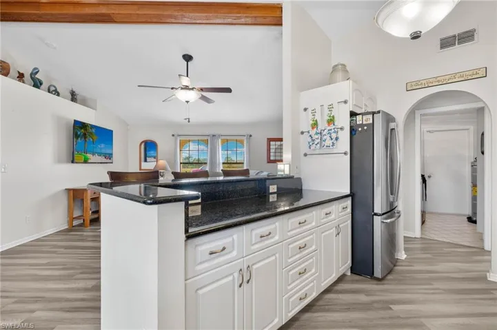 Kitchen is opening to living space that has exposed wooden beam