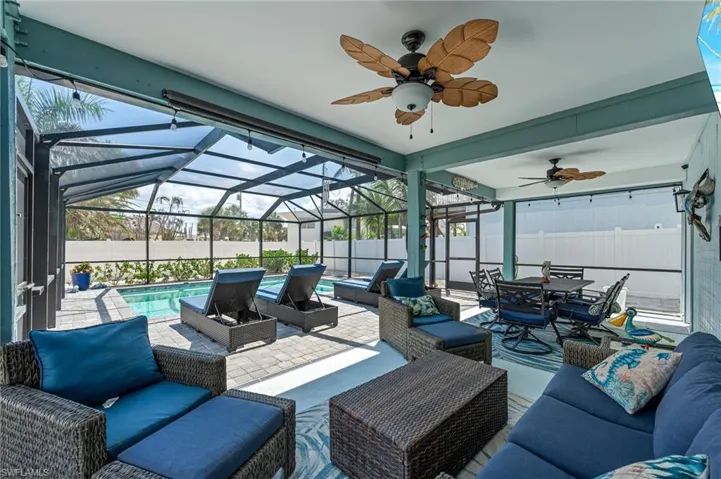 View of patio with outdoor lounge area, a ceiling fan, a fenced backyard, and glass enclosure