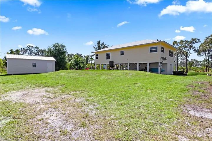 View of the rear of the home and the spacious lawn - the metal building is an Amazon building with high ratings and is currently being used as a hobby room with electrical attachments from the main home.  Just one more added bonus to this one of a kidn property!