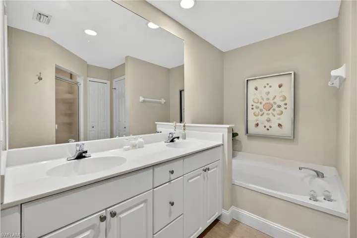 Full bath with double vanity, a stall shower, a garden tub, recessed lighting, and a closet
