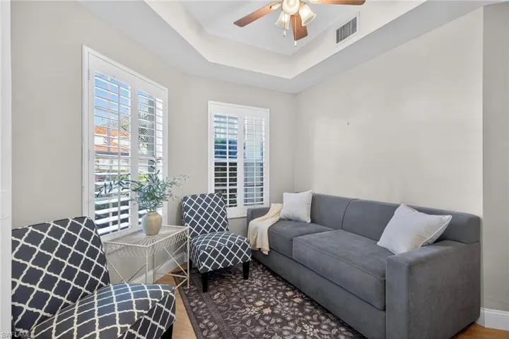 Sitting room with wood finished floors, a raised ceiling, and a ceiling fan