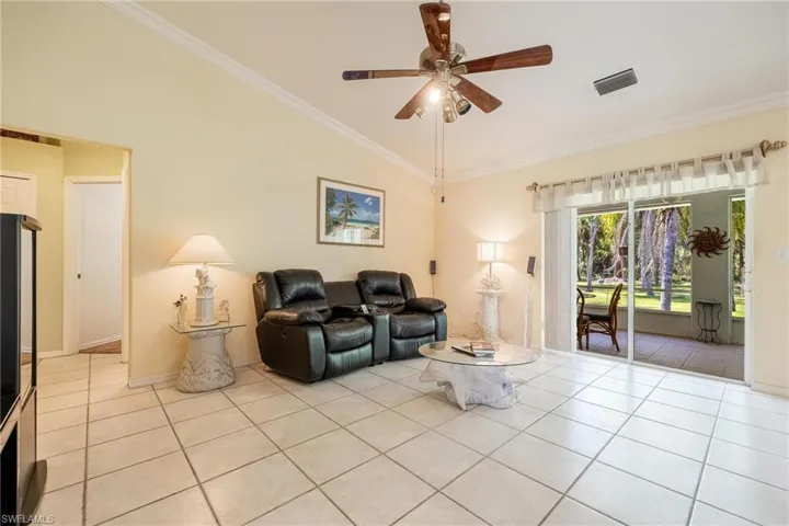 Family room with lofted ceiling, ceiling fan, light tile patterned floors, and crown molding