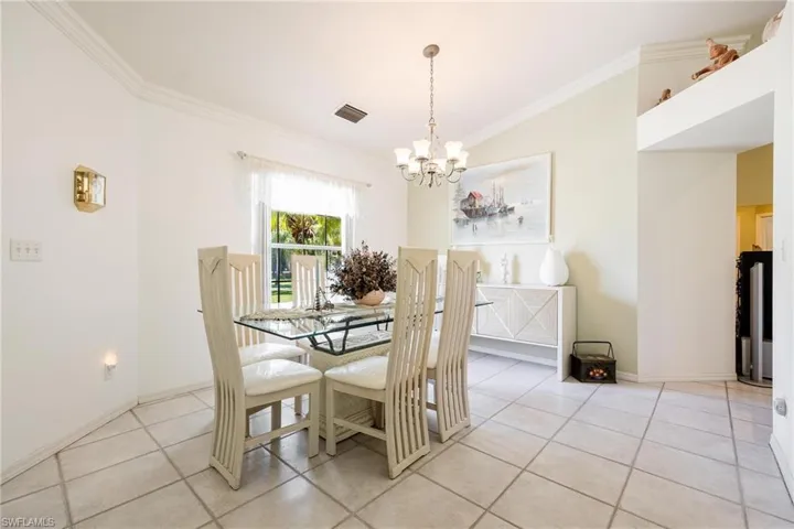 Formal dining area featuring crown molding, light tile patterned floors, and a chandelier