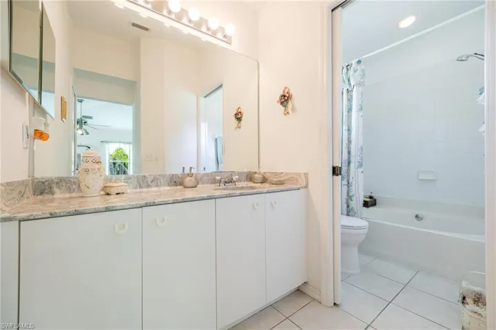 Full bathroom with vanity, tile patterned flooring, ceiling fan, shower / tub combo with curtain, and toilet