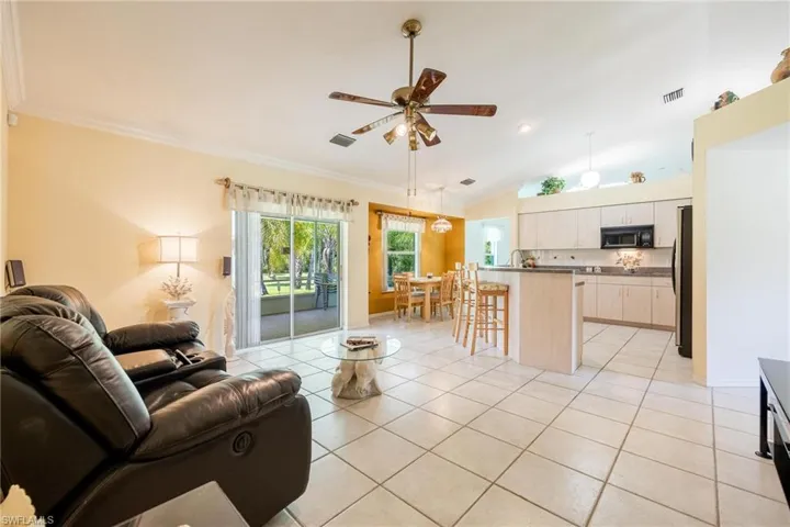 Tiled family room with ceiling fan, vaulted ceiling, and crown molding