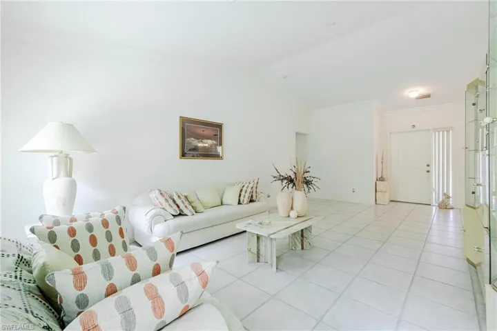 Living room with crown molding, vaulted ceiling, and light tile patterned floors