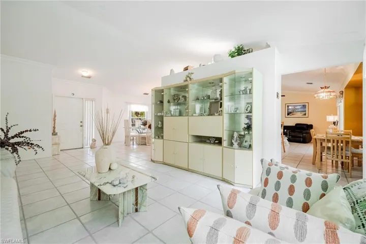 Tiled living room featuring a notable chandelier and crown molding