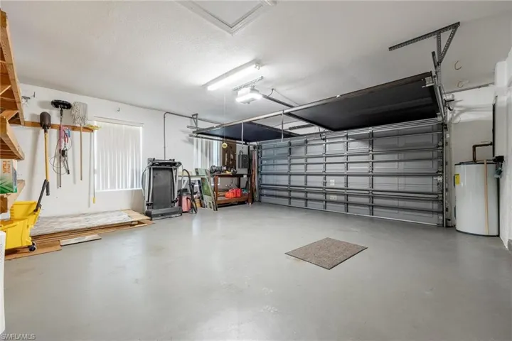 Garage featuring water heater, washer/dryer/sink, screen, and a garage door.