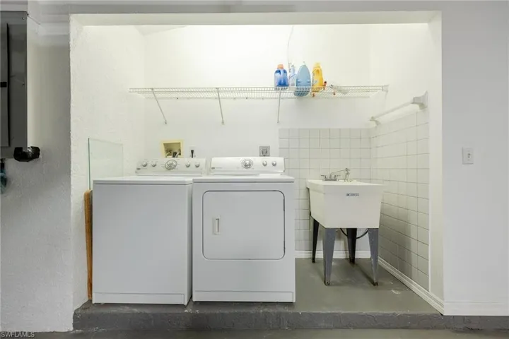 Clothes washing area with washer and clothes dryer and tile walls