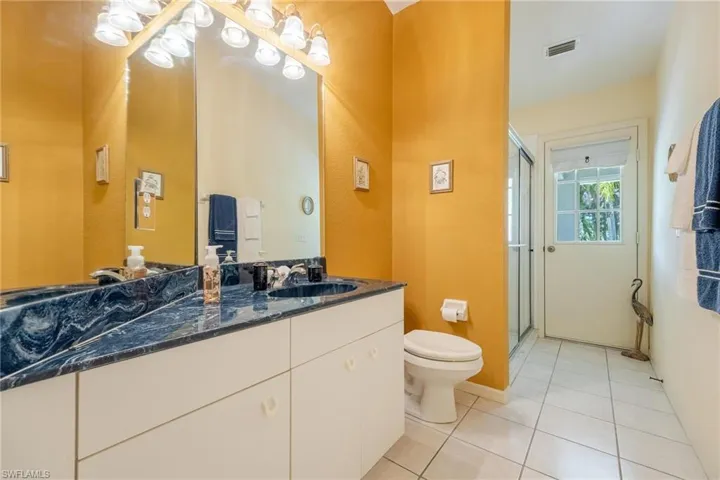 Bathroom featuring tile patterned flooring, vanity, toilet, and an enclosed shower.  Door to backyard or future pool.