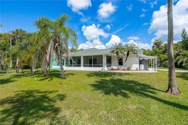 Rear view of property with a screened lanai and a beautiful yard