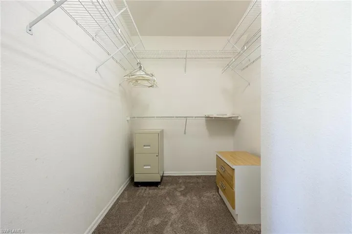 Spacious walk-in closet with dark colored carpet