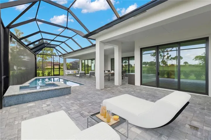 View of patio featuring outdoor lounge area, an in ground hot tub, and glass enclosure