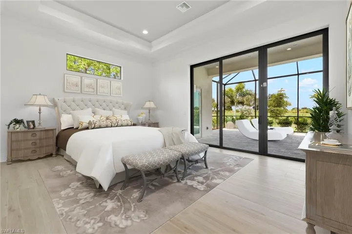Bedroom featuring ornamental molding, light wood-type flooring, access to outside, and a raised ceiling