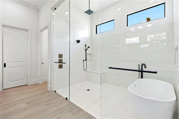 Bathroom featuring wood-type flooring, ornamental molding, and plus walk in shower