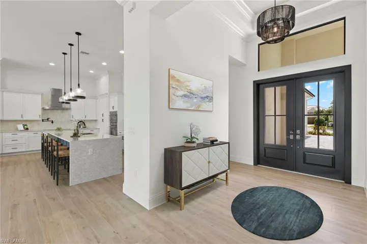 Foyer with a towering ceiling, sink, french doors, ornamental molding, and light hardwood / wood-style flooring