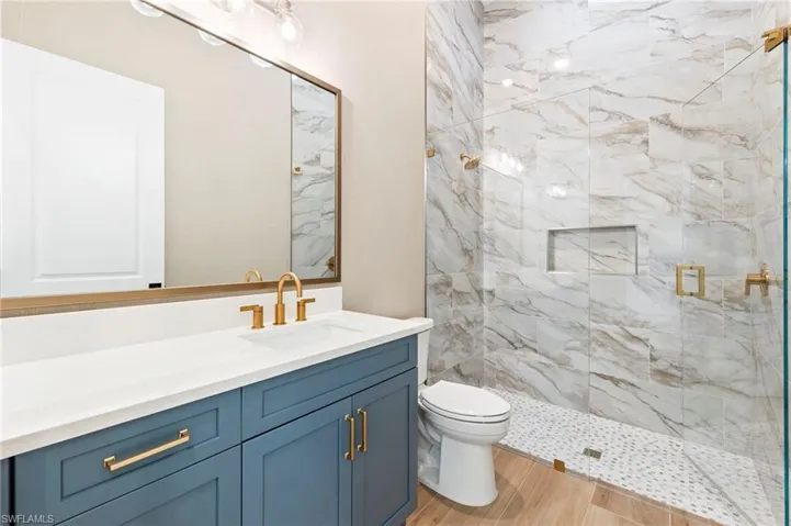 Bathroom with vanity, toilet, wood-type flooring, and tiled shower