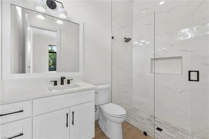 Bathroom with toilet, hardwood / wood-style floors, vanity, and a shower with door