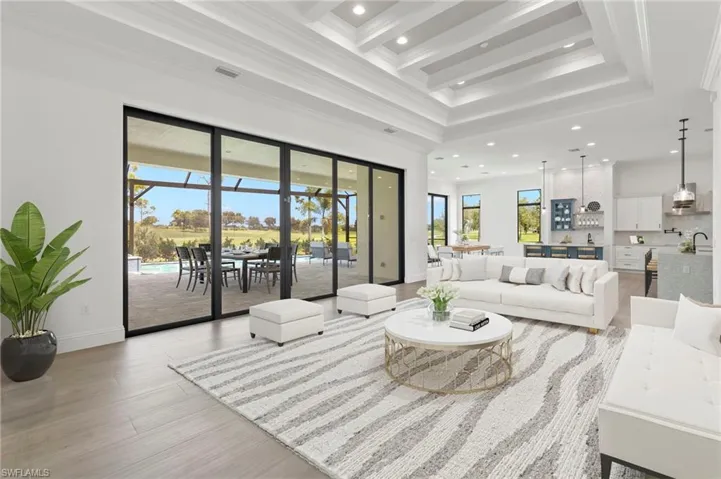 Living room featuring beamed ceiling, ornamental molding, light hardwood / wood-style floors, and plenty of natural light