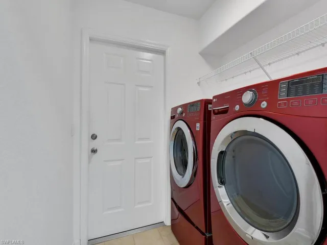 Washroom with separate washer and dryer and light tile patterned floors