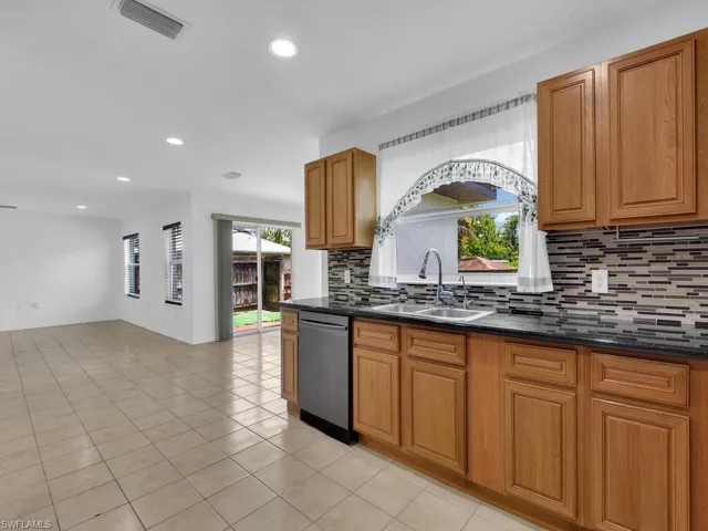 Kitchen featuring recessed lighting, tasteful backsplash, stainless steel dishwasher, light tile patterned floors, and brown cabinets