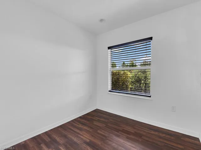 Empty room featuring dark wood-style flooring and baseboards
