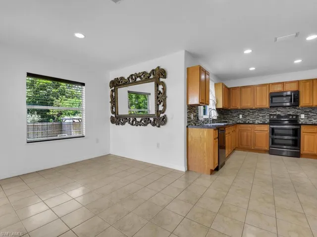 Kitchen featuring plenty of natural light, dark countertops, decorative backsplash, recessed lighting, and stainless steel appliances