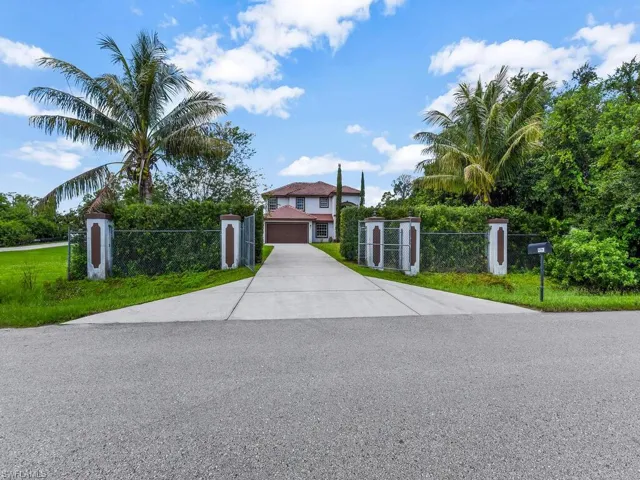 View of front of home featuring driveway and a gate