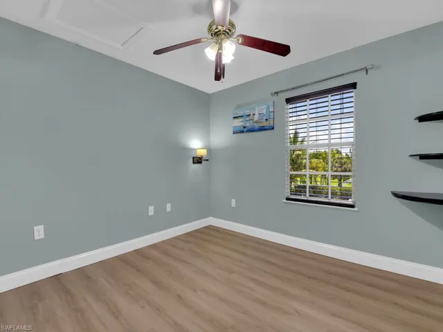 Unfurnished room with wood finished floors, ceiling fan, and attic access