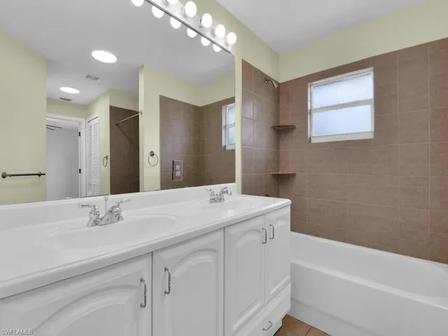 Full bath featuring double vanity, shower / tub combination, and tile patterned flooring