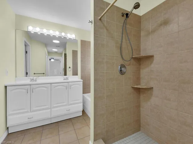 Full bathroom featuring a tile shower, a ceiling fan, double vanity, and tile patterned flooring