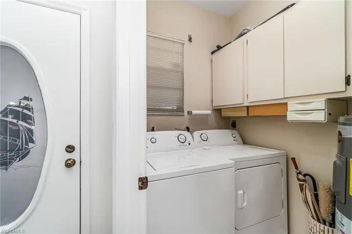 Laundry area featuring washing machine and dryer, electric water heater, and cabinet space