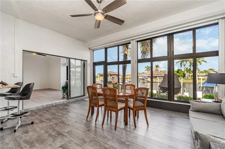 Sunroom featuring a water view, ceiling fan, a textured ceiling, a residential view, and a textured wall