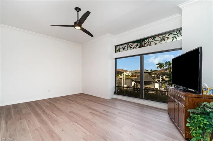 Living area with crown molding, light wood-style flooring, and a ceiling fan