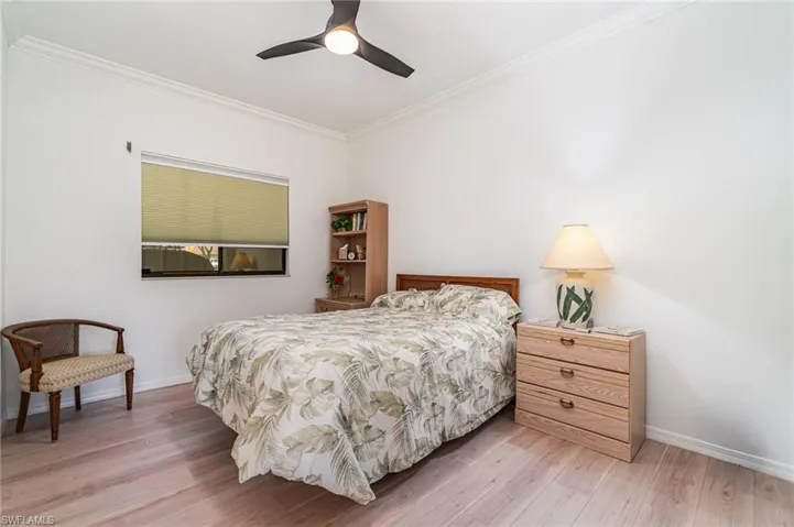 Bedroom featuring crown molding, light wood-type flooring, and ceiling fan